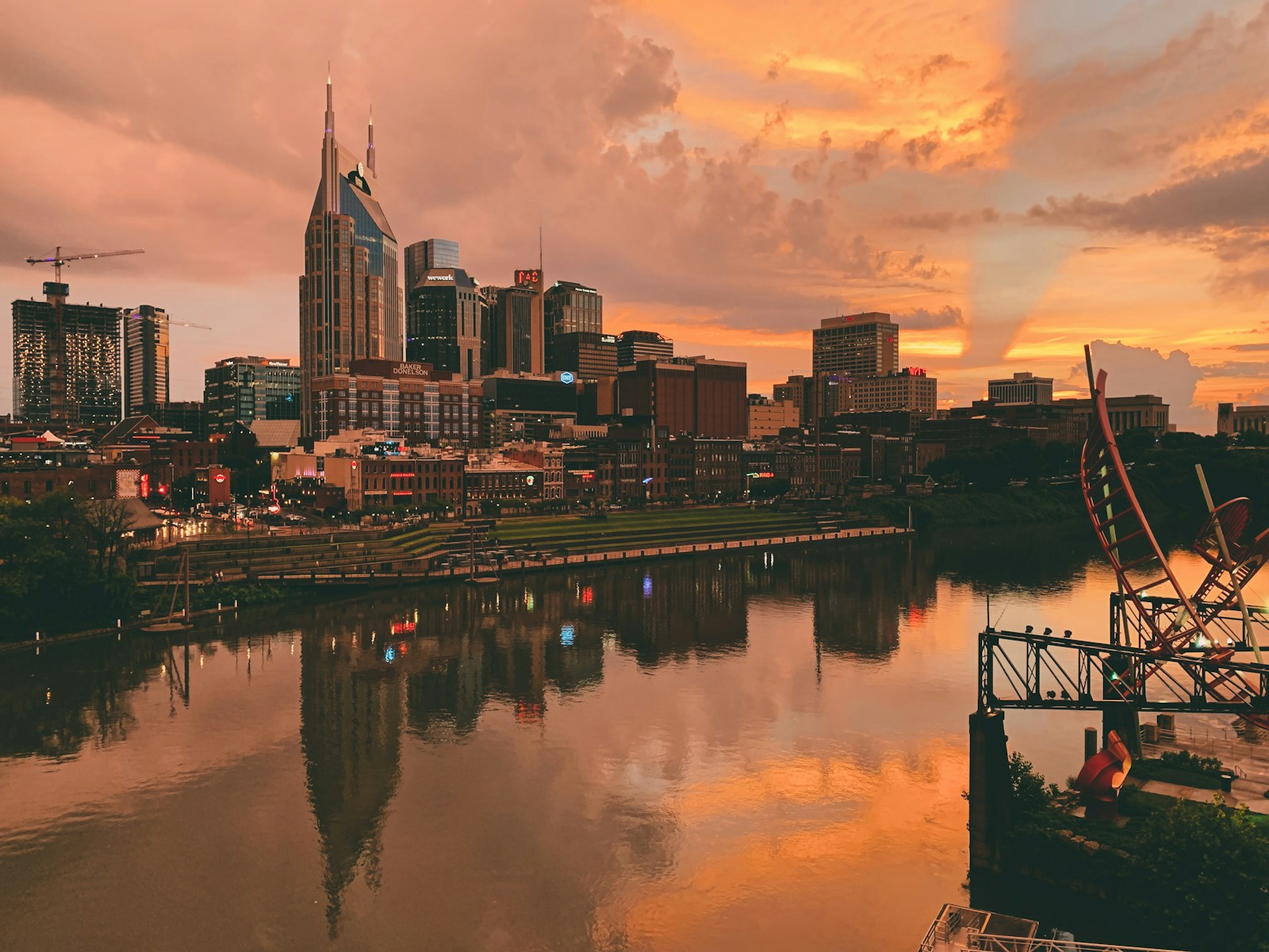 body of water near city buildings during sunset. nashville
