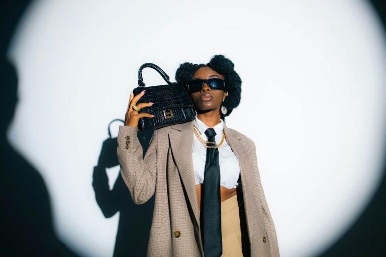 A woman in a coat and tie holding a purse. oversized blazer