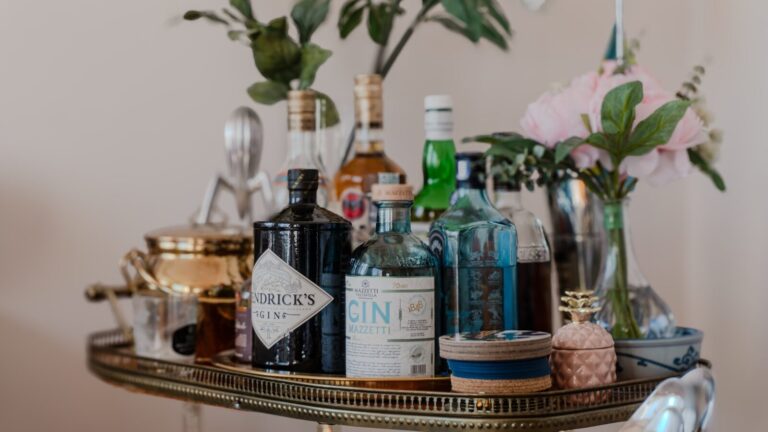 a table topped with bottles of liquor and flowers. cocktails